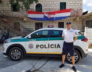 Sierż. szt. Robert Piasecki pełniący służbę w Trogirze stoi przy radiowiozie