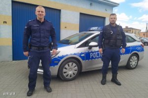1 Sierżant sztabowy Paweł Kaczmarkiewicz i sierżant Miłosz Mrugalski przed garażami i radiowozem