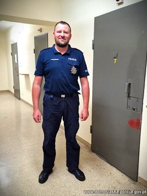 policjant stoi na korytarzu przy otwartych drzwiach