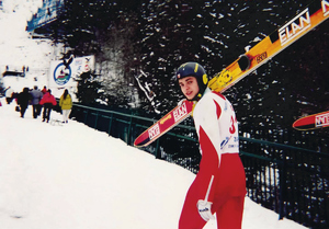 narciarz wspina się na górę z nartami na ramieniu