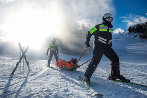 policjanci na nartach jadą po stoku i pomagają potrzebującym