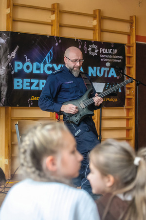 policjant gitarzysta na spotkaniu w szkole otoczony dziećmi