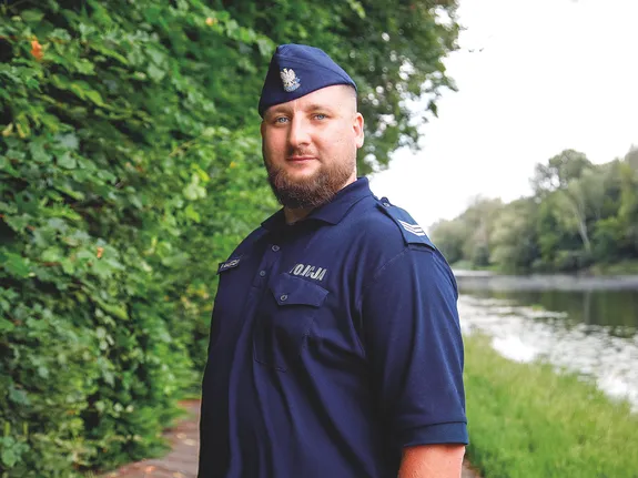 policjant odbiera podziękowania od zastępcy komebndanta i pozuje na tle drzew