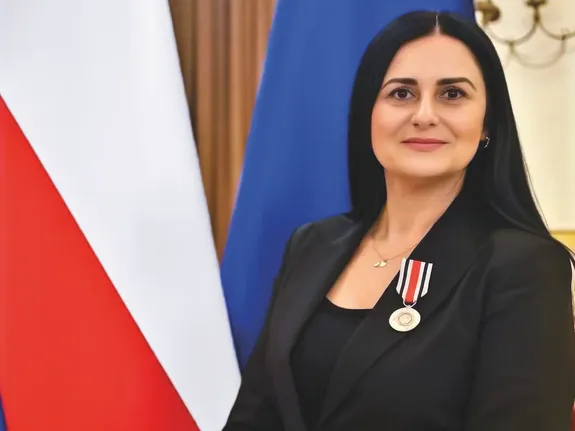 kobieta z materiału pozuje do zdjęcia na tle flag