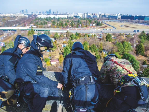 policjanci na dachu patrzą w dół przez barierki