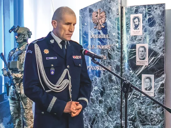 komendant przemawia obok tablicy pamięci w budynku CPKP