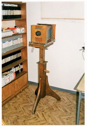 w starym pomieszczeniu stoi stary aparat fotograficzny na podstawce