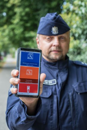 policjant pokazuje aplikację na telefonie o komunikacji z głuchoniemymi