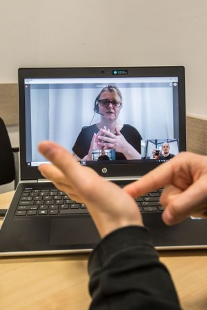 kontakt z głuchoniemym w komendzie policji. na ekranie komputera wyświetla się obraz tłumaczki języka migowego