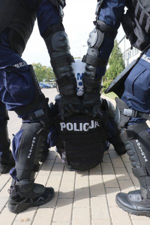 trzech policjantów prezentuje sposób wyciągania rannego policjanta