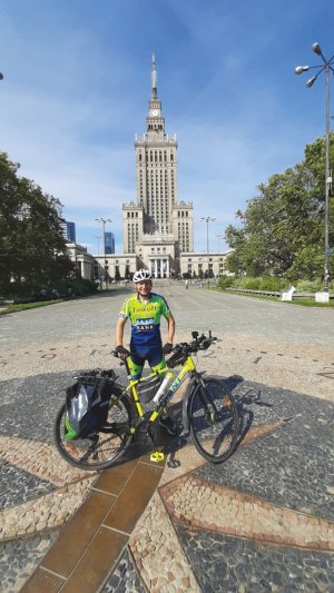Tomasz Dzierga stoi przy rowerze w tle pałac kultury i nauki