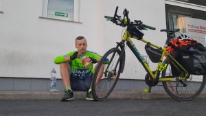 Tomasz Dzierga siedzi przy rowerze i posila się