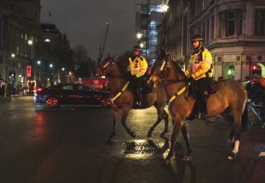 Brytyjscy policjanci jadą przez ulicę konno