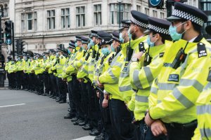 Grupa policjantów brytyjskich w maseczkach stoi w rzędzie