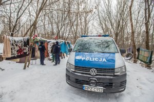 policyjny radiowóz po prawej. policjanci rozmawiają z mieszkańcem prowizorycznego namiotu ustawionego na śniegu
