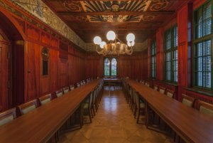 Renowacja polichromii w Sali Tradycji odsłoniła fryderycjańskiego orła znajdującego się we wszystkich pruskich urzędach co widzimy na zdjęci z sali tradycji po bokach długie stoły z krzesłami, na suficie wisi żyrandol z pięcioma świecącymi kulami. całosc w boazerii