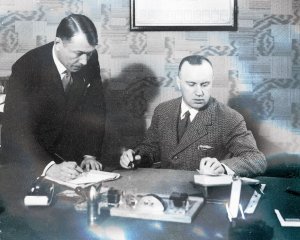 Antoni Sitkowski i Leon Przygoda skan starej fotografii stoją przy biurku a jeden siedzi już...