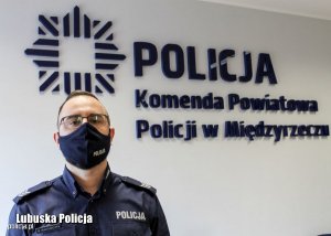 Sierżant sztabowy Mateusz Maksimczyk stoi w pomieszczeniu w tle gwiazda policyjna