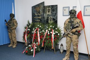 dwaj uzbrojeni funkcjonariusze BOA mają wartę honorową przy tablicy upamiętniającej poległych na służbie