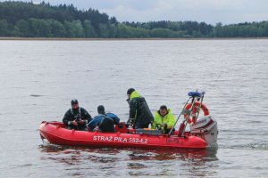 Grupa ratowników płynie po wodzie pontonem. Wydaje się, że chcą wskoczyć do wody by poćwiczyć