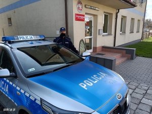 5_sierż. Rafał Domański stoi przed budynkiem policji ale za samochodem policyjnym