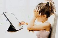 dziecko siedzi przed tabletem i klika w ekran