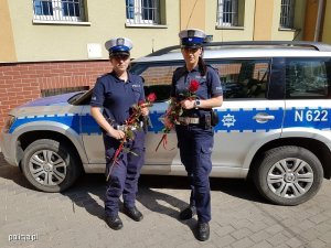 sierż szt. Weronika Krzysztofik sierż Dominika Mucha stoją przed radiowozem trzymając róże otrzymane od uratowanego