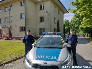sierżant sztabowy Marcin Grabka i posterunkowy Karol Kochanowski stoją przy radiowozie przy budynku policji