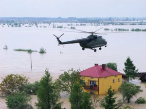 Mi-8 w akcji ratowniczej podczas powodzi leci nad zalanymi terenami i budynkiem zalanym wodą