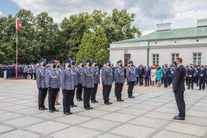Podczas uroczystości Prezydent RP Andrzej Duda wręczył odznaczenia państwowe grupa policjantów stoi w szyku przed prezydentem na placu