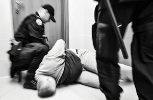 policjant obezwładnia agresora i wykonuje czynności unieruchamiające