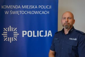 asp. Rafał Skrzypczak na tle napisu policja