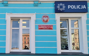 niebieska  ściana budynku policji z tabliczkami policyjnymi oznaczającymi przeznaczenie