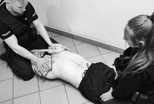 policjanci prowadzą pierwszą pomoc dla osoby niespokojnej wymagającej unieruchomienia w celu pomocy medycznej