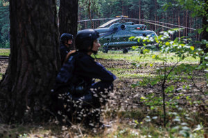 policjanci ćwiczą w lesie w powietrzu z wykorzystaniem śmigłowca Mi-8 uzbrojeni strzelający biegający w dymie i ukrywają się wśród drzew