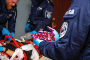dekoracyjne foto dłonie policjanta ubrane w rękawiczki lateksowe są ubrudzone czymś co przypomina krew