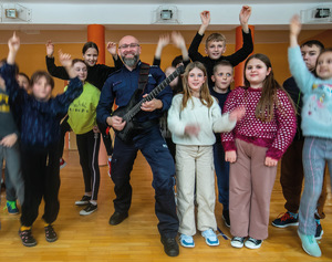 policjant gitarzysta na spotkaniu w szkole otoczony dziećmi