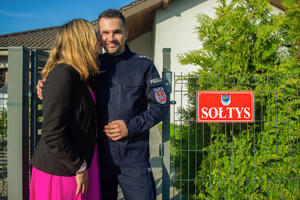 policjant z żoną przed domem z napisem sołtys