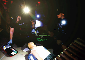 policjanci ratują w ciemności oświetlając latarkami ciemność