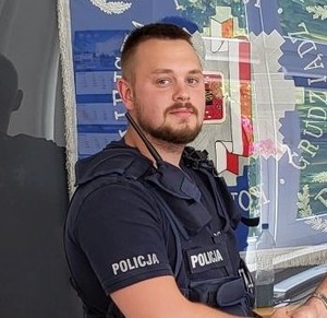 policjanci stoją przy radiowozach i przy budynkach pozując do zdjęcia do materiału