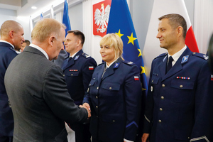 policjantka przyjmuje uścisk od ministra SWiA w tle godło