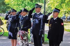 policjanci składają wieńce na pomniku i salutują nie widać dokładnie czemu, ale można się domyślać, że po złożeniu wieńców zasalutowali oddając honor w uroczystości