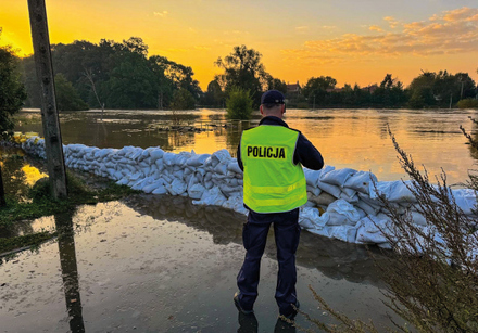 policjanci podczas powodzi ratują ludzi. sypią piach do worków, wynoszą na plecach z domów osoby, holują na pontonie poszkodowanych i ich dobytek