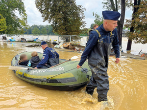 policjanci podczas powodzi ratują ludzi. sypią piach do worków, wynoszą na plecach z domów osoby, holują na pontonie poszkodowanych i ich dobytek