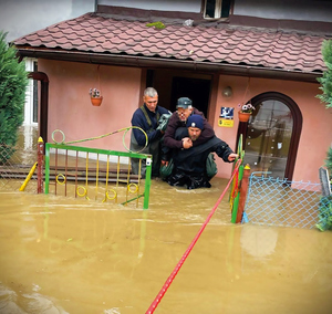 policjanci podczas powodzi ratują ludzi. sypią piach do worków, wynoszą na plecach z domów osoby, holują na pontonie poszkodowanych i ich dobytek