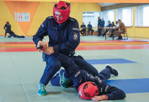 policjanci ćwiczą na macie jeden leży drugi nad nim