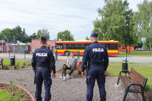 policjanci legitymują siedzącego na ław2ce młodzieńca