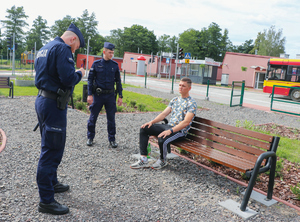 policjanci legitymują siedzącego na ław2ce młodzieńca