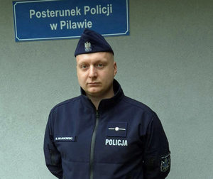 policjanci na tle ściany z napisem policja