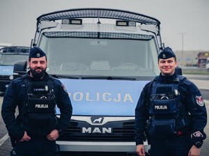 policjaNCI Z MATERIAŁU STOJą przy radiowozach w budynkach i obok nich